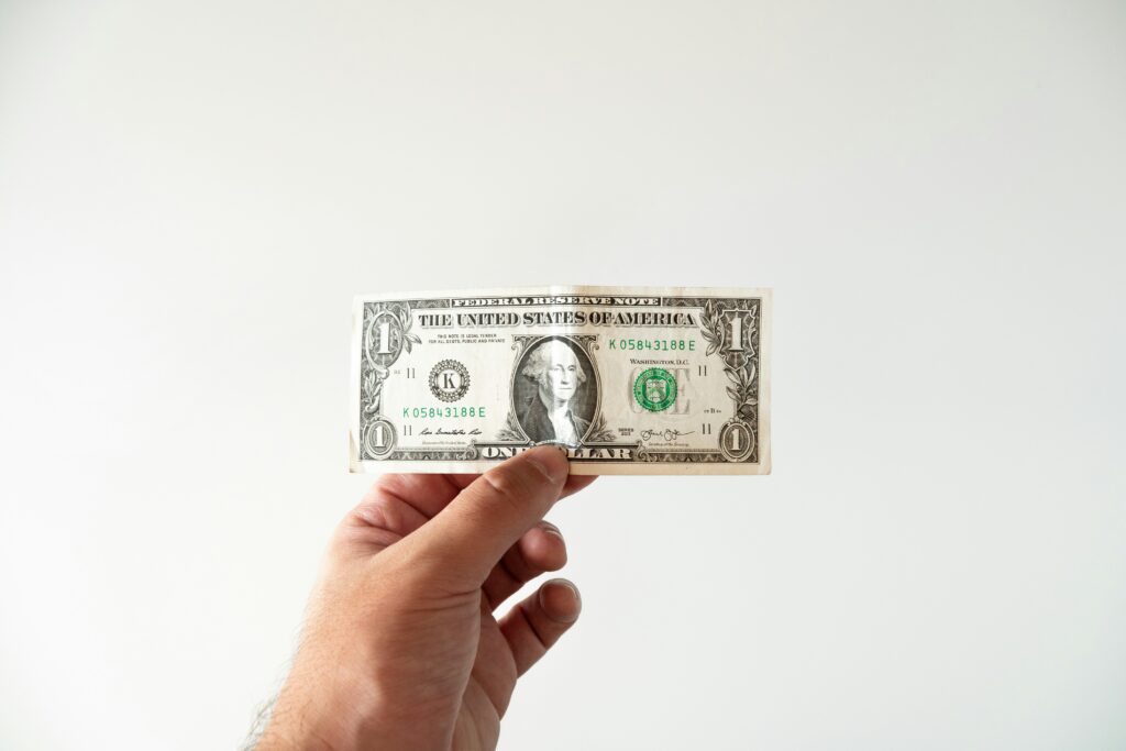 片手で1ドル札を持つ手元のクローズアップ
