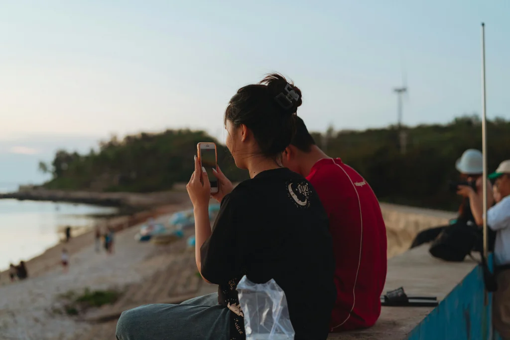 お揃いのTシャツを着て、スマートフォンを手にハーリーの熱気あふれる港を眺める女性