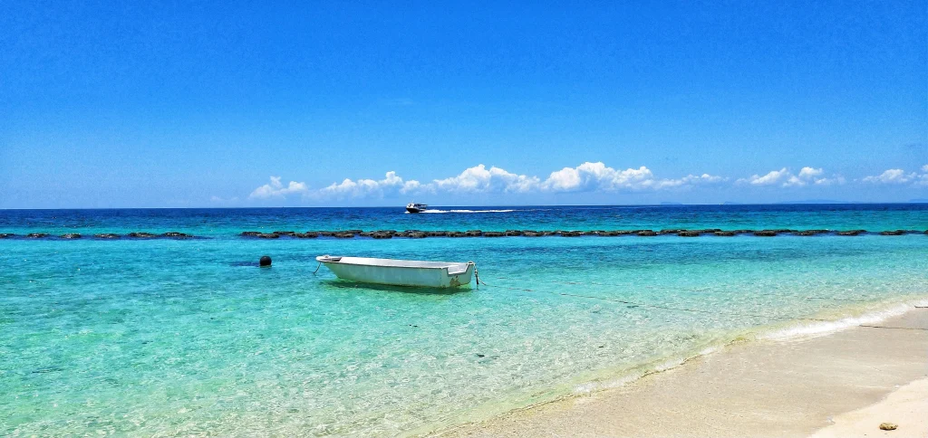 海に浮かぶ小さな木造ボートと遠くの水平線に広がる青い空の風景