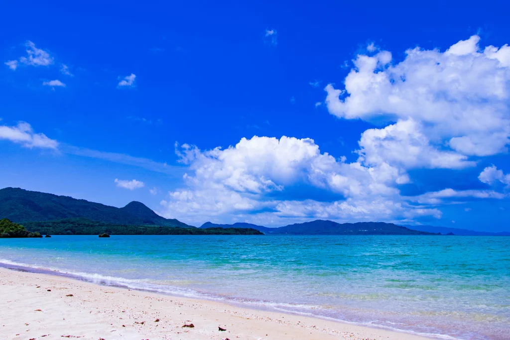 白い雲が浮かぶ広大な青い空とエメラルドグリーンの美しい海の風景